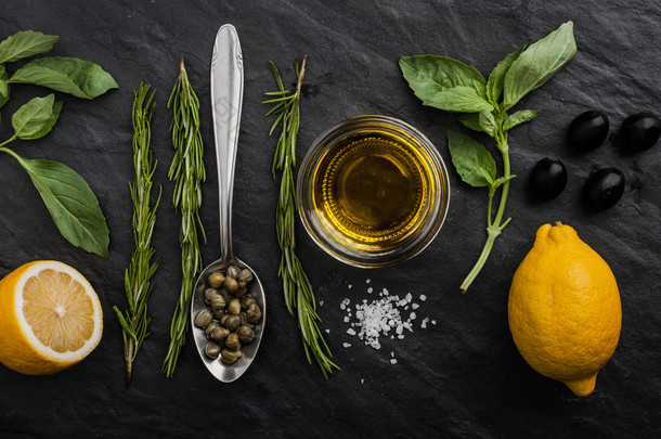 Herbs mix with  lemons , capers and olives on the black stone table