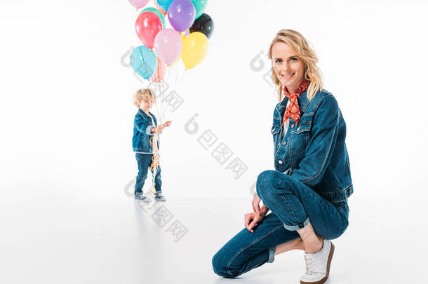 儿子散步气球和母亲<strong>蹲</strong>在前景上白色