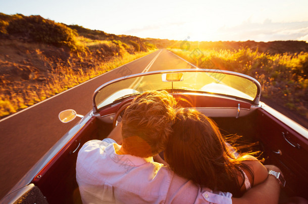 浪漫的情侣在日落时分在美丽的路上行驶