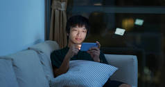 男人晚上在手机上玩网络游戏