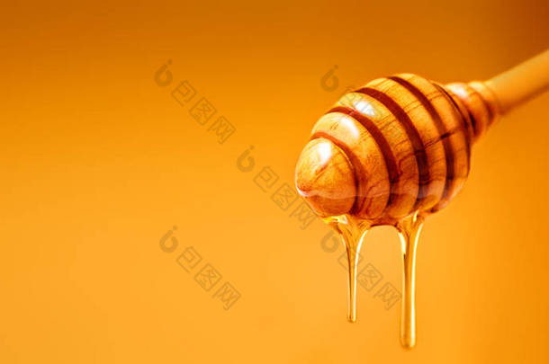 <strong>蜂蜜</strong>从木<strong>蜂蜜</strong>滴水在黄色<strong>背景</strong>。甜蜂产品为您的设计与 copyspace.