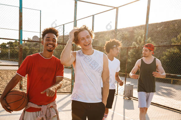 照片的肌肉运动男子微笑和举行的球, 而站在<strong>篮球</strong>场户外在夏季阳光明媚的一天