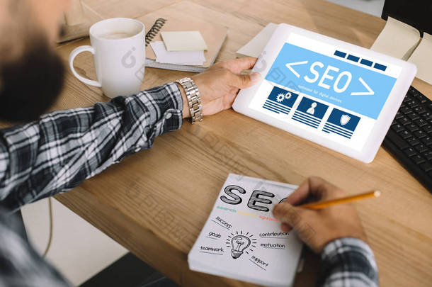 在工作场所使用 tablet 和书写笔记的 seo 经理裁剪镜头