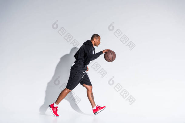 年轻的非洲裔美国运动员的侧面看蓝球打篮球 
