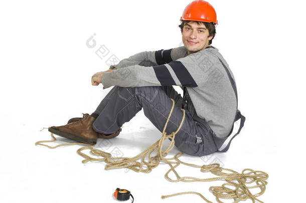 一个年轻的工人在灰色制服绑在白色隔离背景的绳子.