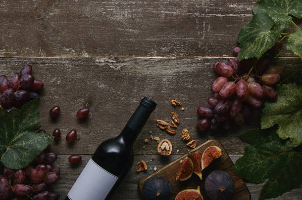 葡萄酒瓶上的空白标签, <strong>新鲜</strong>的葡萄, 无花果和<strong>坚果</strong>在木桌上的顶部视图 
