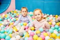 两个可爱的小女孩看着相机, 而坐在五颜六色的气球在主题公园