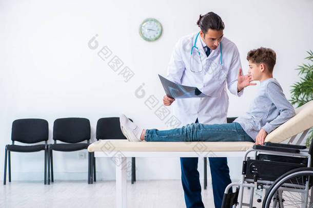 年轻的男医生、儿科医生和坐在<strong>轮椅</strong>上的男孩