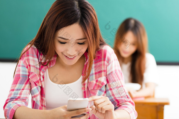 年轻的女学生在教室里使用智能手机
