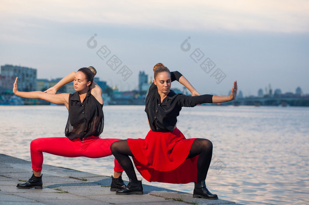 两个年轻漂亮的双胞胎姐妹在河附近的城市背景中起舞，waacking 舞蹈.