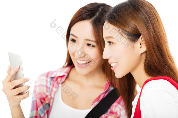 看着智能手机的两个快乐的青少年学生女孩