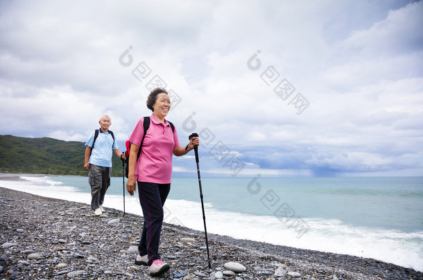 幸福的高级夫妇在海岸沙滩上徒步旅行