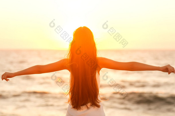 自由的女人享受自由海滩在日落时分感觉幸福.