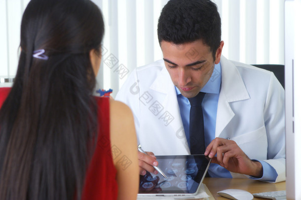 西班牙裔医生与病人伏案审查脑 x 光线在平板电脑上