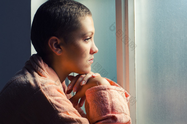 年轻的癌症病人站在医院的窗户