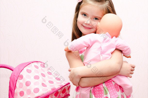 可爱微笑的小女孩玩她的玩具马车和娃娃