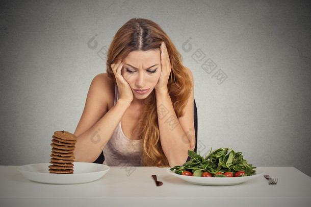 女人累的饮食限制决定吃健康的食物或甜饼干 