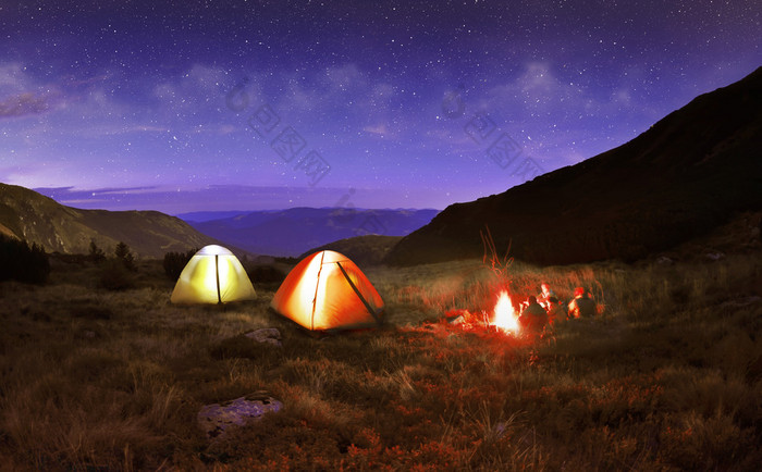 在夜晚的星空下照明黄色野营帐篷