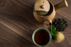 陶瓷茶壶，杯红茶薄荷叶和红糖木制的桌子上