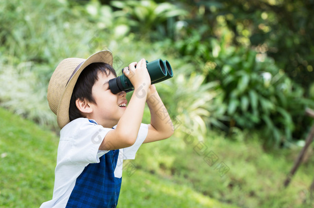 看海槽双筒望远镜与<strong>微笑</strong>的脸在公园的小亚洲男孩