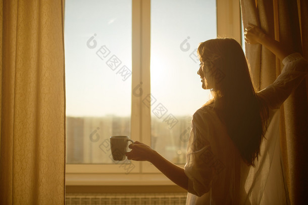 女子捧着杯茶，看一看日出