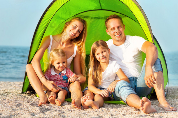 在沙滩上露营的快乐年轻家庭