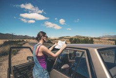 女人站在阅读地图的旧车。Swartberg。西方