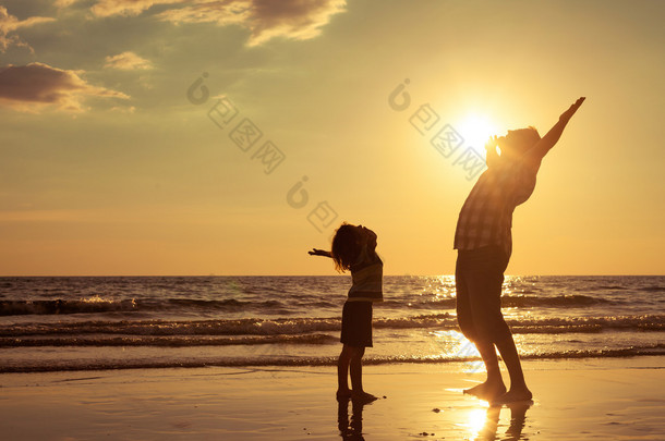 父亲和儿子在日落的时候在海滩上玩.