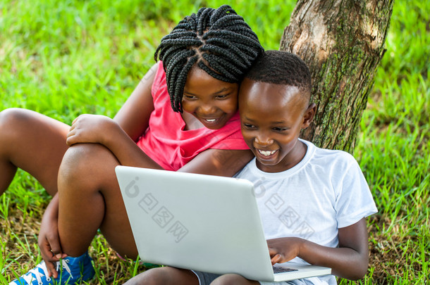 非洲男孩和女孩在玩笔记本电脑.