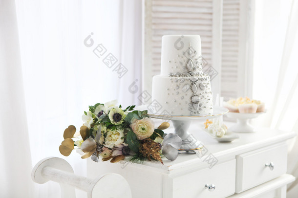婚礼花束与银装饰的白色婚礼蛋糕