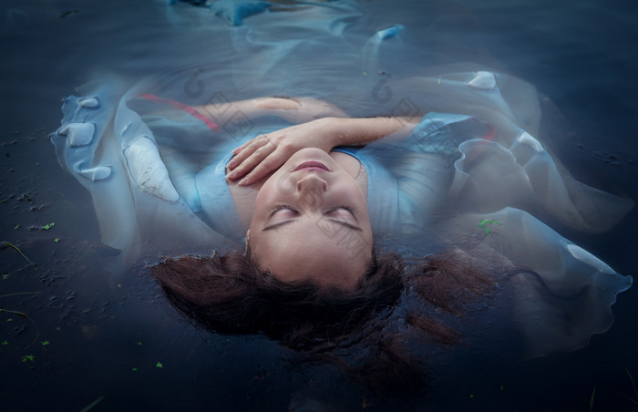 年轻美女穿着蓝色的衣服躺在水中淹死
