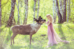 在童话打扮和驯鹿在森林里的女孩