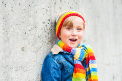 可爱的蹒跚学步的男孩穿着色彩鲜艳的帽子和围巾的室外肖像