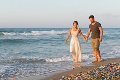 对年轻的夫妇喜欢在黄昏时在朦胧的海滩上散步.