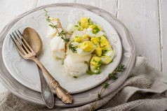 白色的水煮的鱼鳕鱼配酱基于黄油和煮鸡蛋