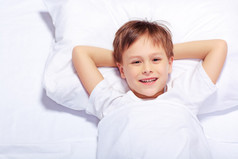 一个可爱的情感的小男孩躺在床上的肖像
