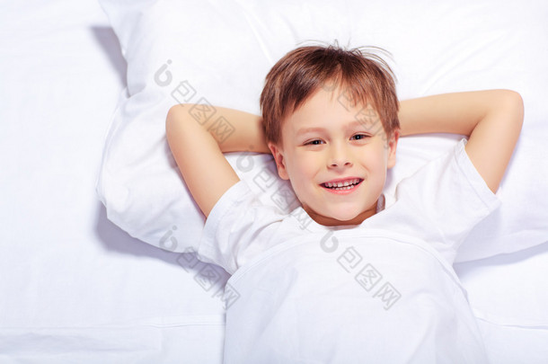 一个可爱的情感的小男孩躺在<strong>床上</strong>的肖像