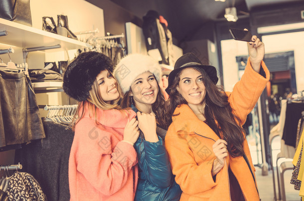 三个女人采取自拍照穿彩色大衣