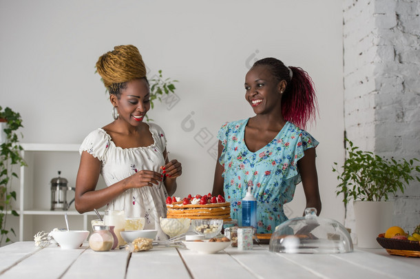 非洲妇女烹饪与草莓蛋糕