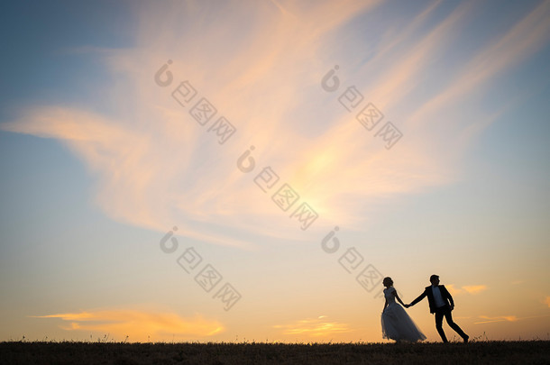 年轻的新婚夫妇走上红太阳背景字段