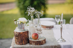 野生花卉在玻璃瓶和金属桶上节日的餐桌，婚礼表