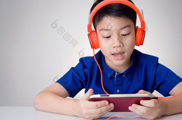 亚洲男孩洁具耳机和玩手机