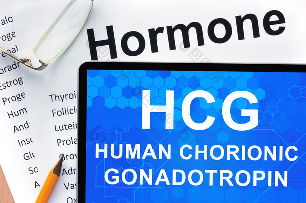 Papers with hormones list and tablet  with words  Human chorionic gonadotropin (HCG) .