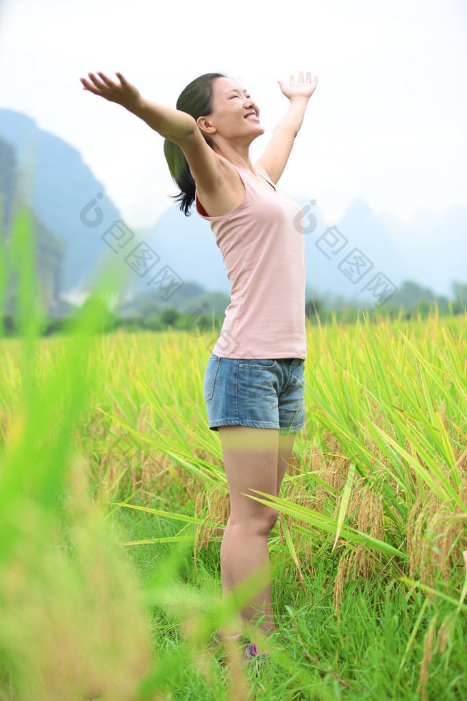 年轻的亚洲女人张开双臂在水田