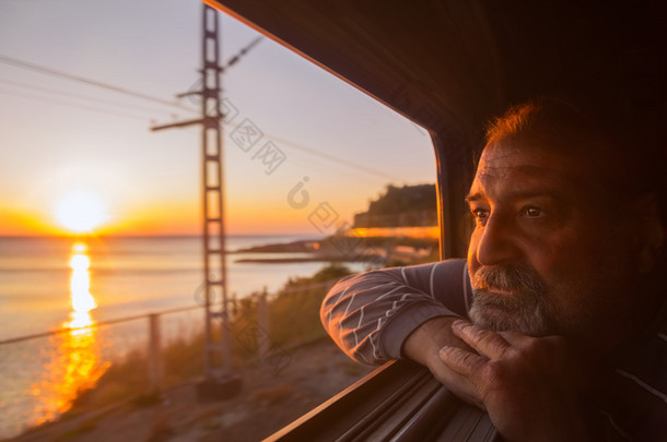 男人欣赏海上日落从火车