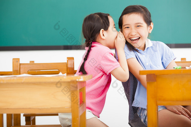 快乐的小<strong>女孩</strong>耳语和分享在教室里的秘密