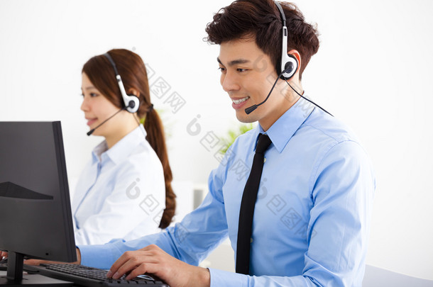 业务的男人微笑着和耳机在办公室工作的女人