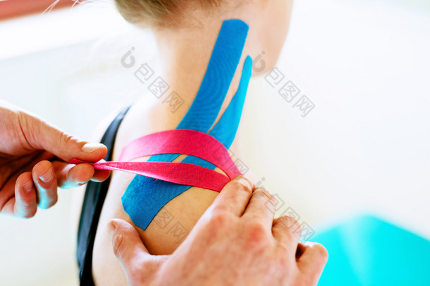治疗师将磁带应用于病人的肩上