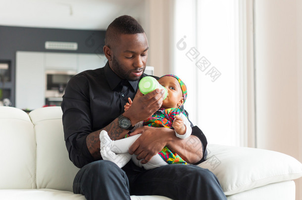 年轻的非洲裔美国父亲给她的宝贝女儿在牛奶