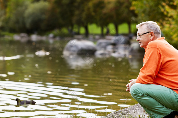 成熟的男人蹲在池塘边